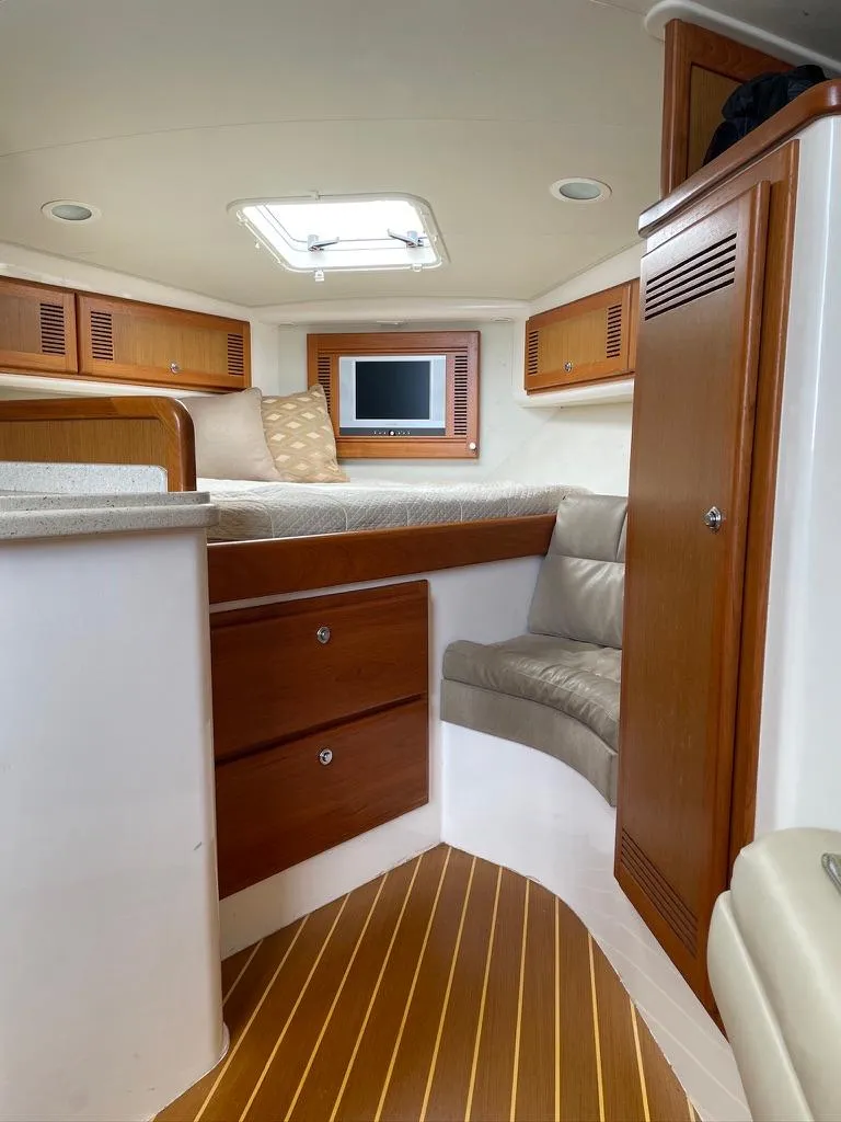 Slide: The Image of 2004 Cabo 35 Express cabin interior with wood finish, bed, and small TV. - 33