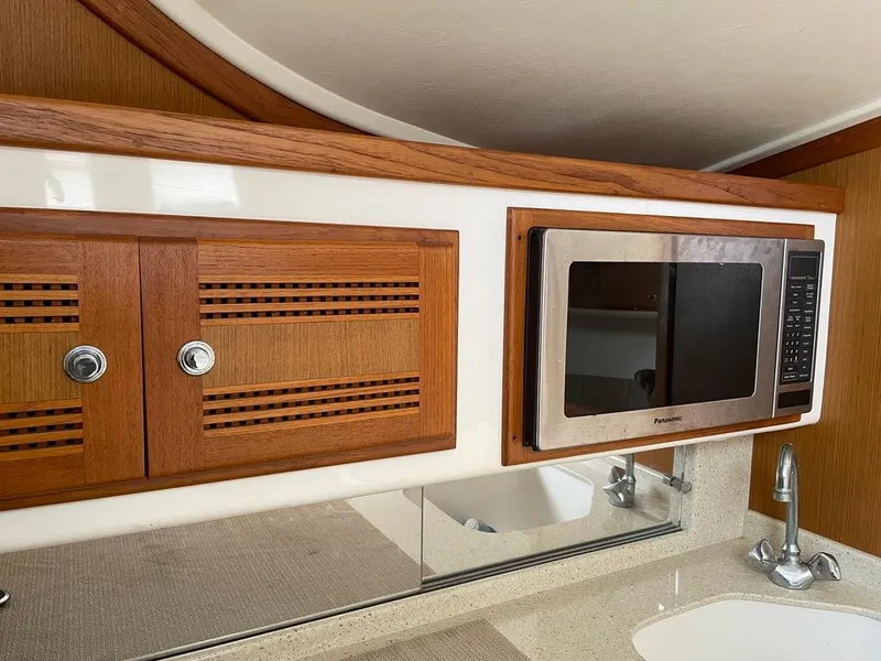 Slide: The Image of 2004 Cabo 35 Express yacht interior with wooden cabinets and built-in microwave. - 38