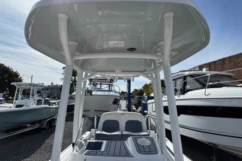 Slide: The Image of 2024 Tidewater 198 CC Adventure boat with T-top, docked among other vessels. - 13