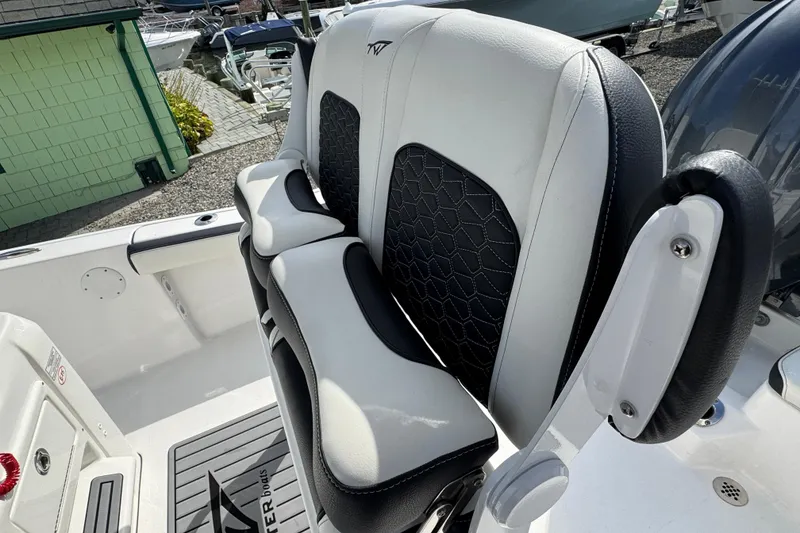 Slide: The Image of 2024 Tidewater 198 CC Adventure boat seat with black and white upholstery, docked outdoors. - 3