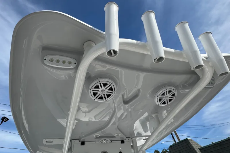 Slide: The Image of 2024 Tidewater 198 CC Adventure boat top with rod holders and speakers under blue sky. - 9