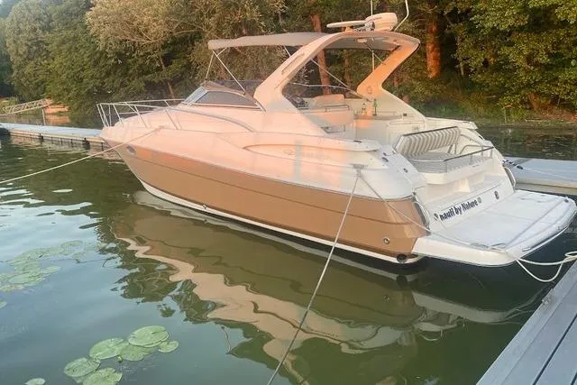 The Image of 2004 Regal Commodore 3560 boat docked on calm water with lush greenery background. - 0
