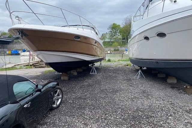 Slide: The Image of 2004 Regal Commodore 3560 boats on stands, parked beside a black convertible car. - 2