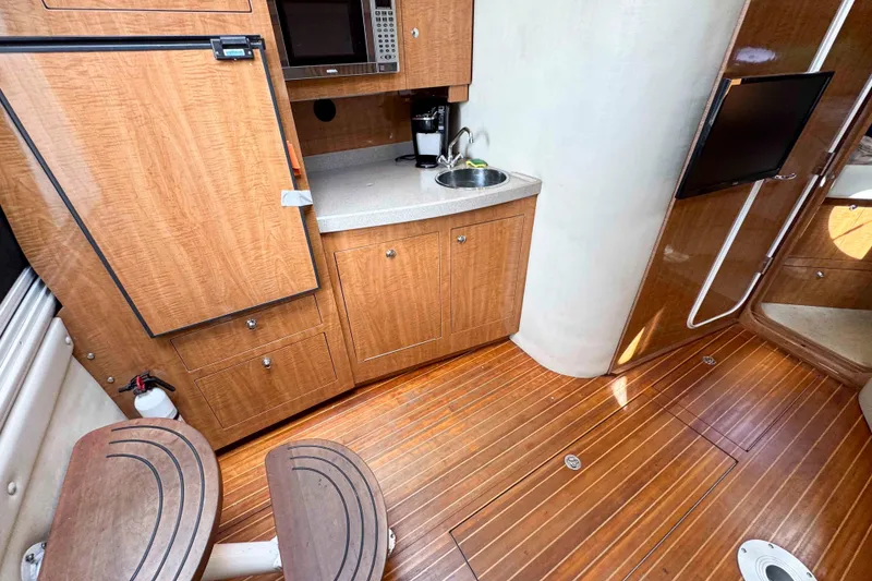 Slide: The Image of 2004 Regal Commodore 3560 yacht interior with wooden cabinetry, kitchenette, and seating area. - 21