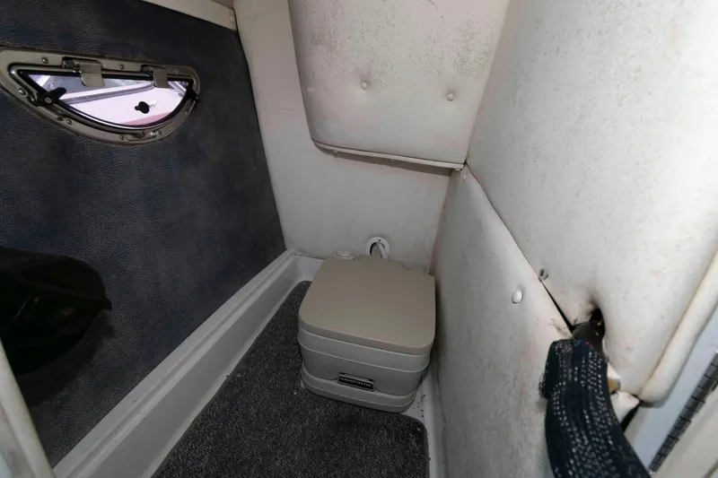 Slide: The Image of 2007 Cobalt 252 boat interior with compact portable toilet and small window. - 11