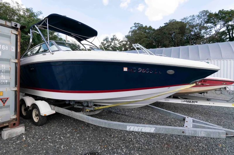 Slide: The Image of 2007 Cobalt 252 boat on trailer, blue and white, parked outdoors. - 2