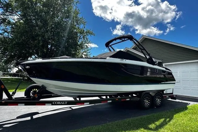 The Image of 2023 Cobalt R8 boat on trailer, parked in driveway under blue sky. - 0