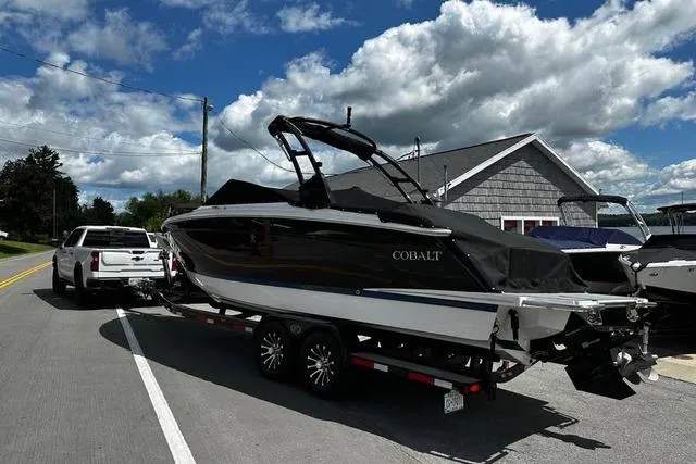 Slide: The Image of 2023 Cobalt R8 boat docked at a marina, featuring sleek black and white design. - 2