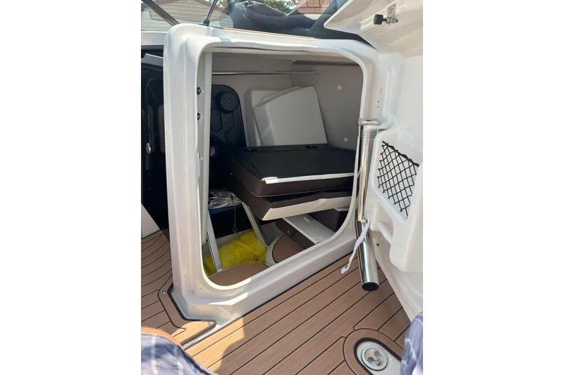 Slide: The Image of 2023 Yamaha Boats 252SD interior storage compartment with wooden flooring and netted pocket. - 8