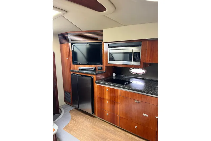 Slide: The Image of 2006 Cruisers Yachts 520 Express kitchen with wood cabinetry, microwave, and TV. - 9