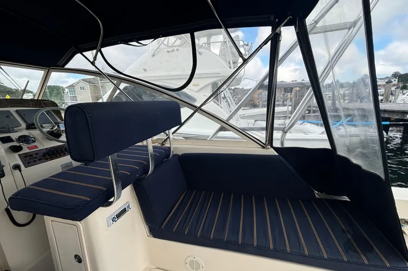Slide: The Image of 2005 Mainship Pilot 34 interior with navy seating and clear canopy, docked at marina. - 10