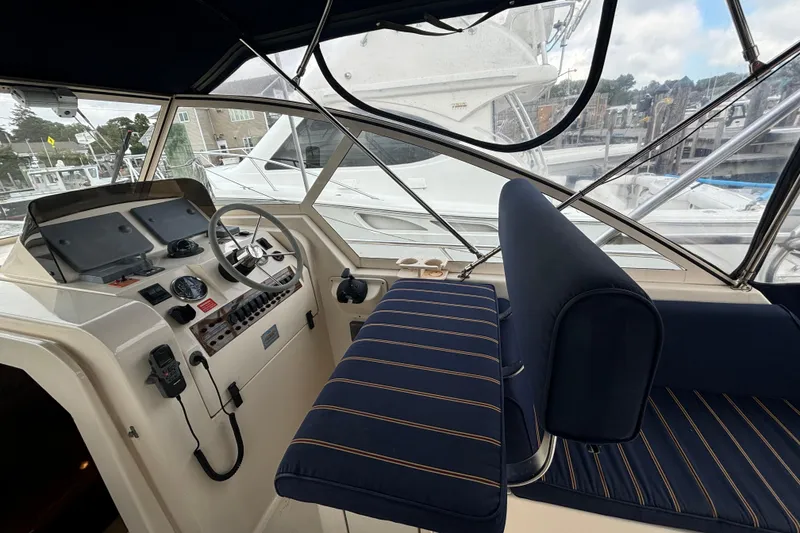 Slide: The Image of 2005 Mainship Pilot 34 interior with navy seating and helm, docked at marina. - 11