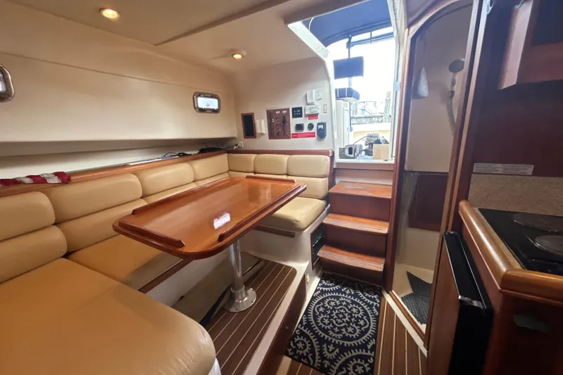 Slide: The Image of 2005 Mainship Pilot 34 interior with kitchenette, dining area, and cozy seating. - 14