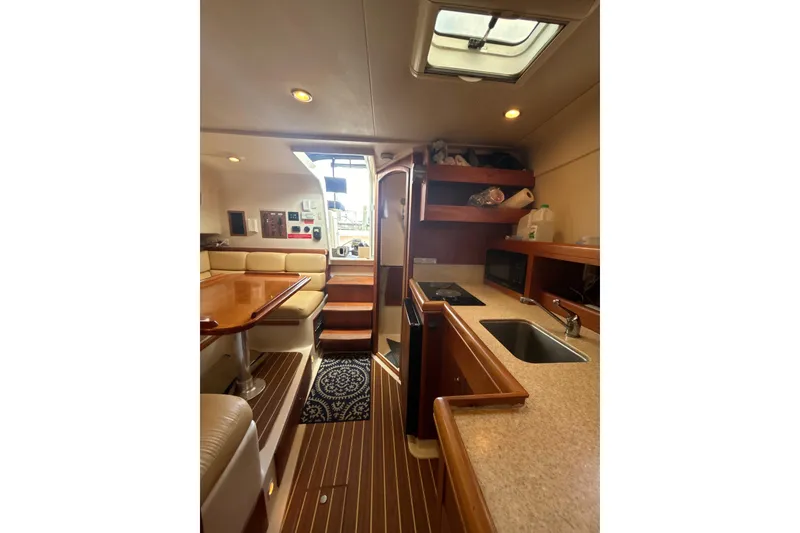Slide: The Image of 2005 Mainship Pilot 34 interior with cozy seating, wooden table, and nautical decor. - 15