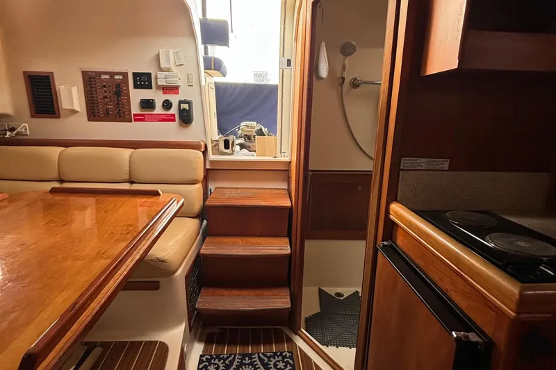 Slide: The Image of 2005 Mainship Pilot 34 interior with kitchenette, dining area, and wooden flooring. - 16