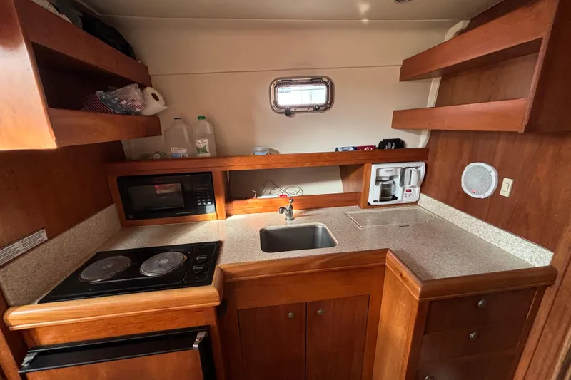 Slide: The Image of 2005 Mainship Pilot 34 interior with beige seating and wooden table. - 19