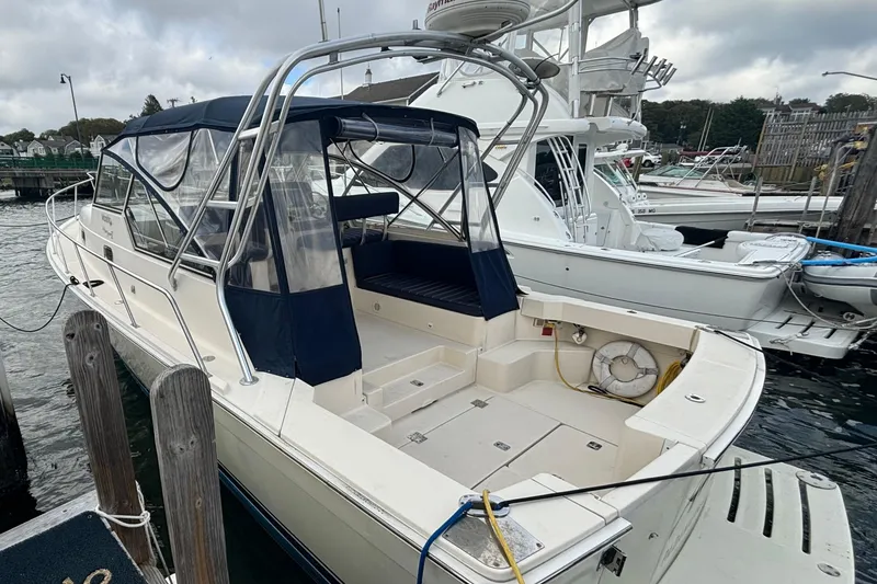 Slide: The Image of 2005 Mainship Pilot 34 docked at marina, featuring blue canopy and spacious deck. - 2