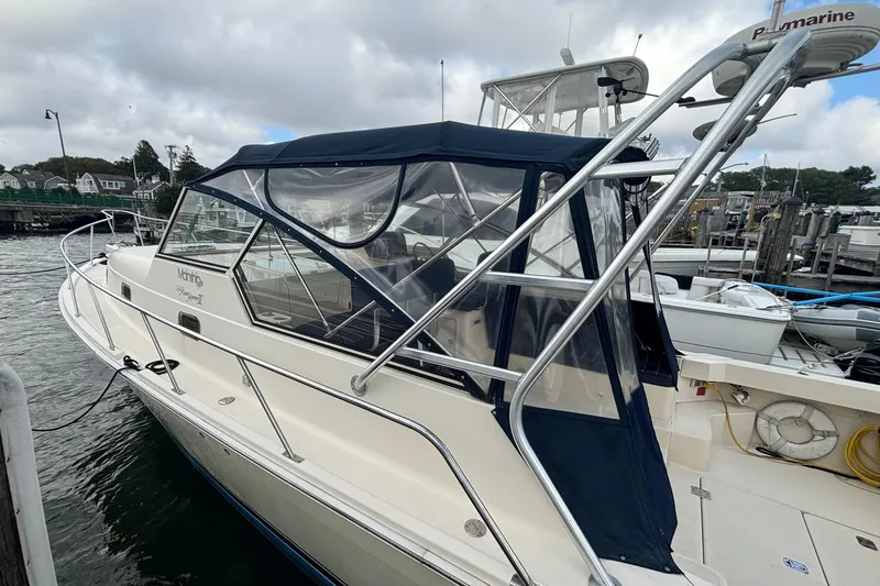 Slide: The Image of 2005 Mainship Pilot 34 boat docked at marina, featuring blue canopy and sleek design. - 3