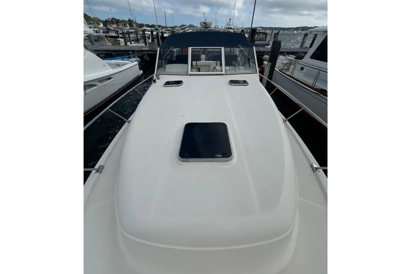 Slide: The Image of 2005 Mainship Pilot 34 docked at marina, cloudy sky, waterfront buildings in background. - 5