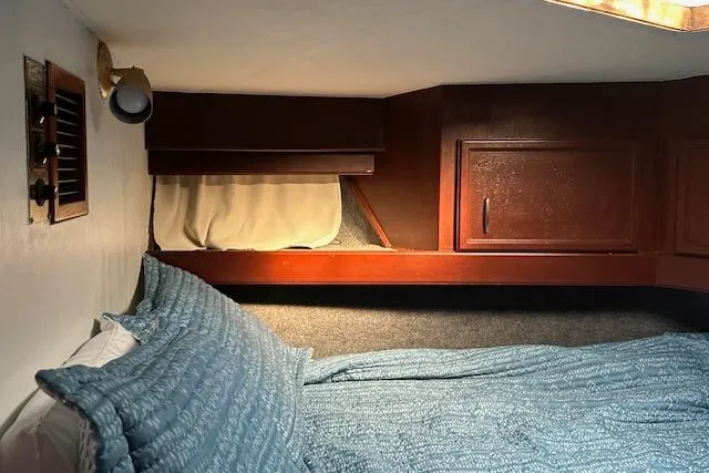 Slide: The Image of 1986 Egg Harbor 37 Convertible cabin interior with blue bedding and wooden cabinetry. - 17