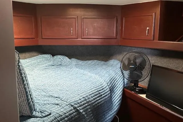 Slide: The Image of Cozy cabin interior of 1986 Egg Harbor 37 Convertible with blue bedding and wooden cabinets. - 18