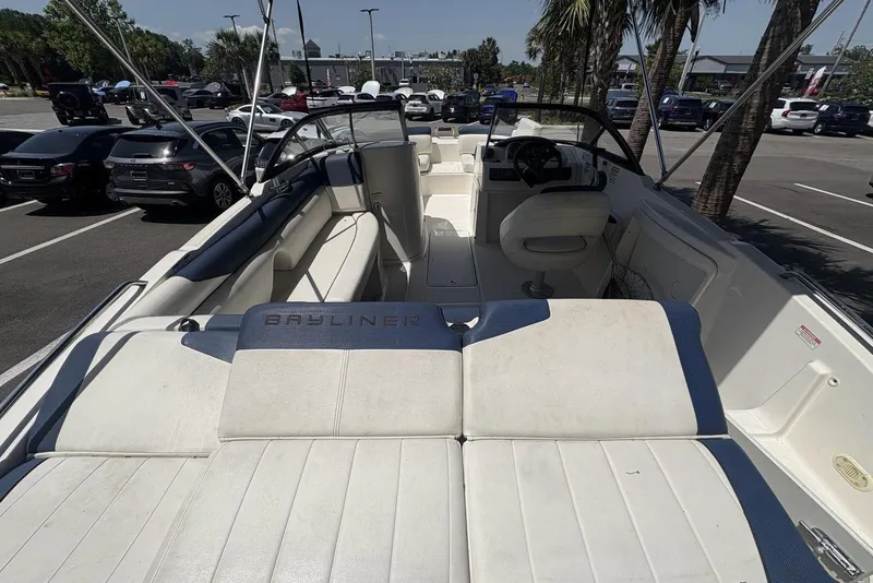 Slide: The Image of 2016 Bayliner 215 Deck Boat interior with seating and steering wheel in a parking lot. - 19