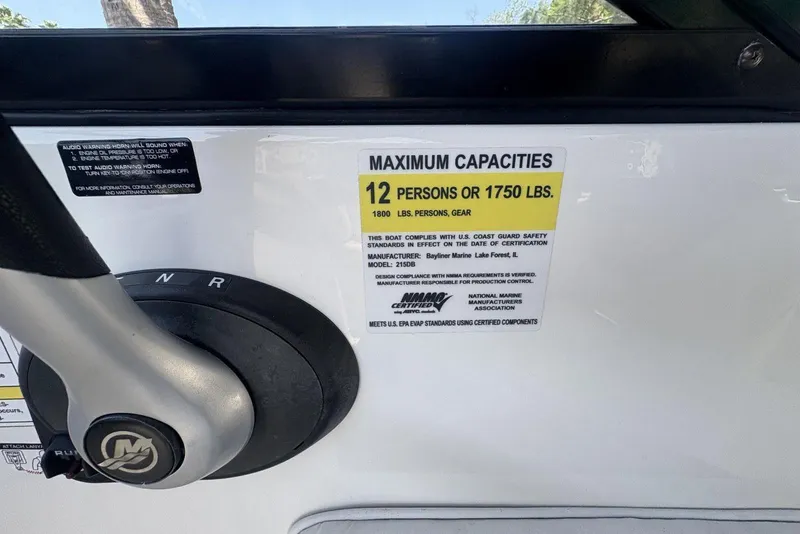 Slide: The Image of 2016 Bayliner 215 Deck Boat capacity label, 12 persons or 1750 lbs, steering wheel visible. - 21