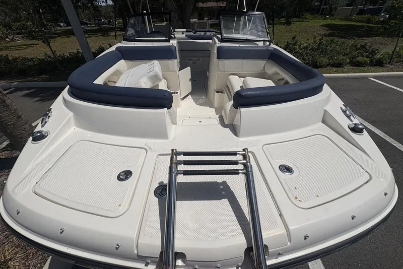 Slide: The Image of 2016 Bayliner 215 Deck Boat with spacious seating and sleek design, parked outdoors. - 24