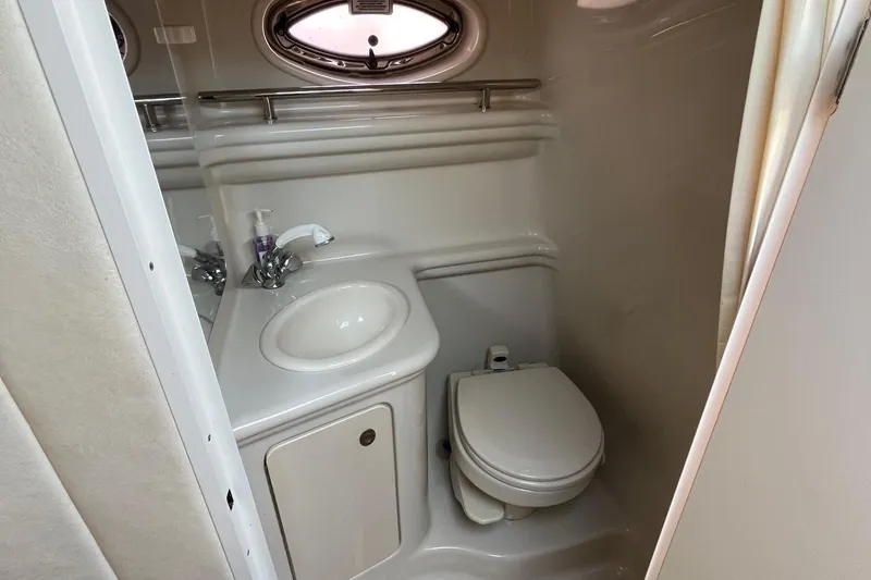 Slide: The Image of 2006 Sea Ray 260 Sundancer bathroom with sink, toilet, and porthole window. - 12