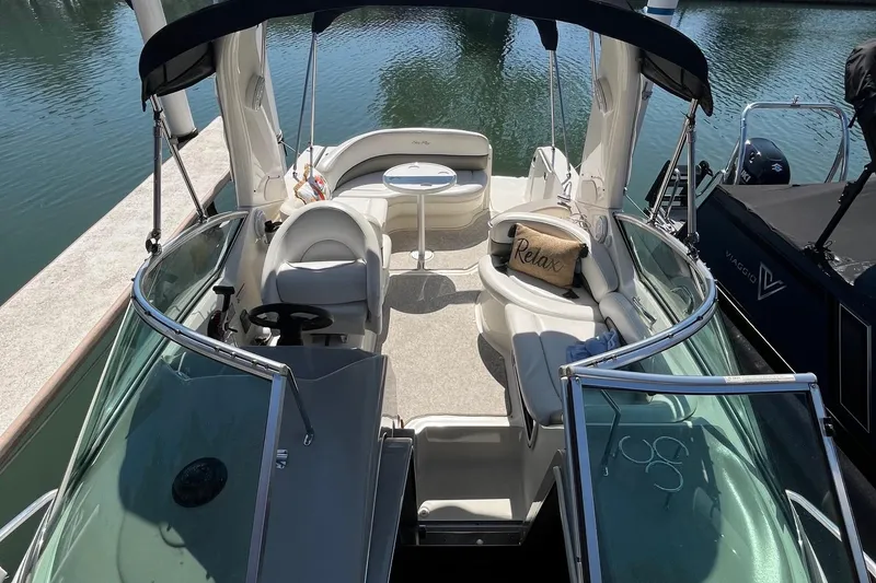 Slide: The Image of 2006 Sea Ray 260 Sundancer boat interior with seating and steering wheel, docked by the water. - 2