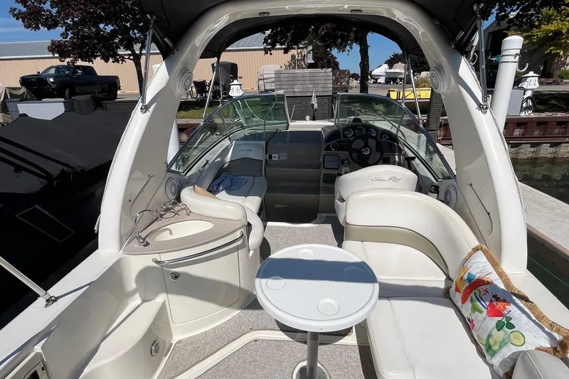 Slide: The Image of 2006 Sea Ray 260 Sundancer boat interior with seating, table, and helm at dock. - 3