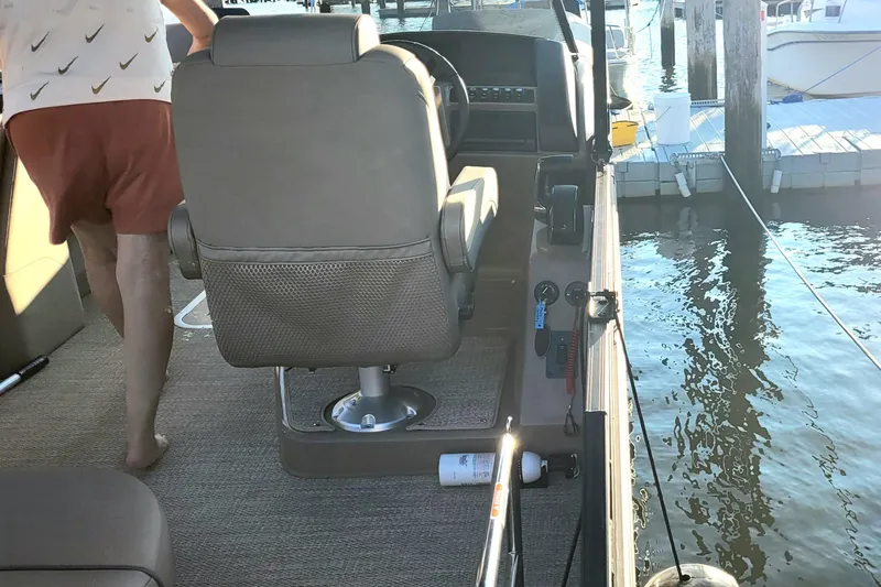 Slide: The Image of 2024 Bennington 24LXSSB boat interior at dock, featuring seating and control panel. - 12