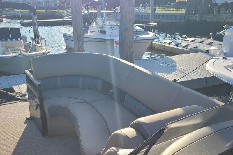 Slide: The Image of 2024 Bennington 24LXSSB pontoon boat with luxurious seating at a marina dock. - 13