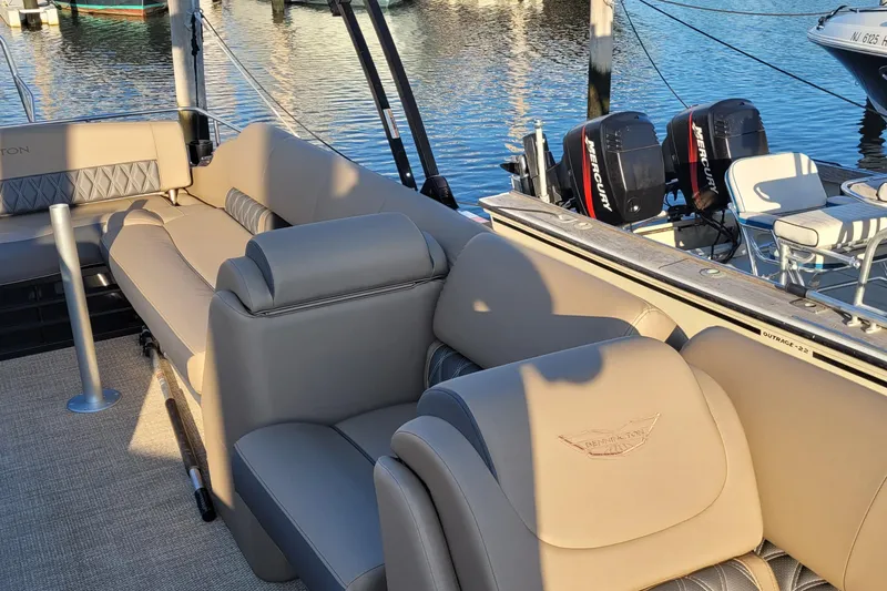 Slide: The Image of 2024 Bennington 24LXSSB pontoon boat interior with beige seating and Mercury engines. - 21
