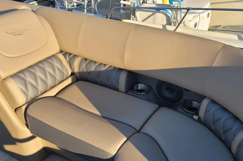 Slide: The Image of 2024 Bennington 24LXSSB boat interior with beige and gray cushioned seating, cup holders, and speaker. - 26