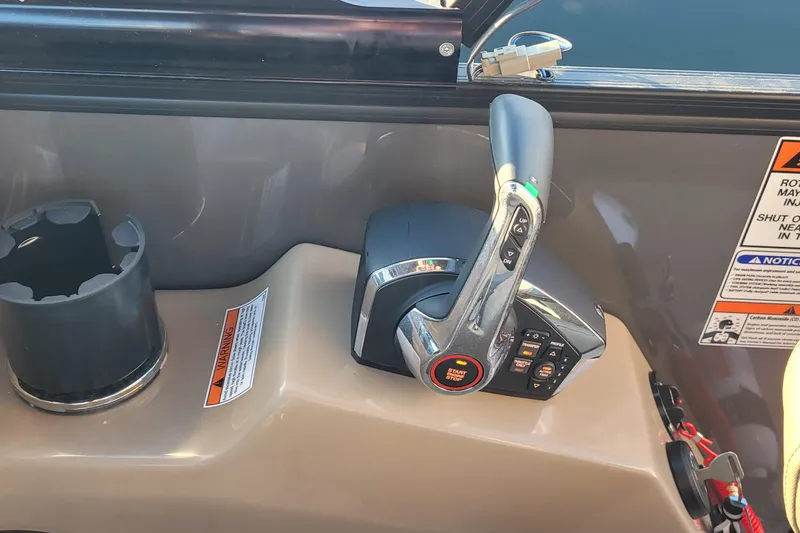 Slide: The Image of 2024 Bennington 24LXSSB boat throttle control with cup holder and warning labels. - 31