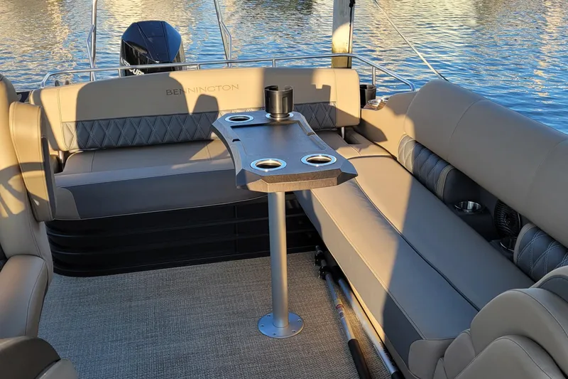 Slide: The Image of 2024 Bennington 24LXSSB pontoon boat interior with seating and table on water. - 36