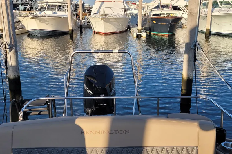 Slide: The Image of 2024 Bennington 24LXSSB boat docked with Mercury engine, surrounded by other boats. - 39