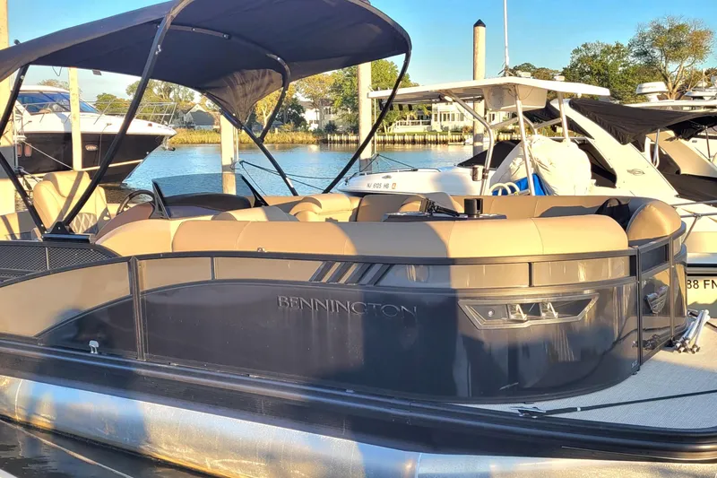 Slide: The Image of 2024 Bennington 24LXSSB pontoon boat docked, featuring sleek design and spacious seating. - 5