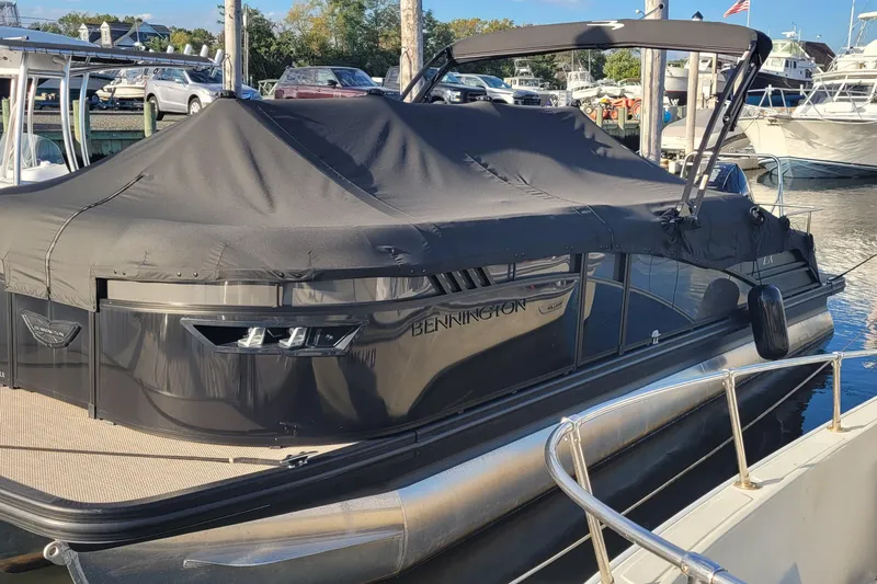 Slide: The Image of 2024 Bennington 24LXSSB pontoon boat covered at a marina dock. - 6