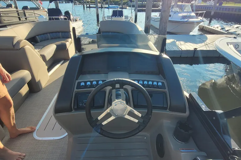 Slide: The Image of 2024 Bennington 24LXSSB boat dashboard with steering wheel, docked at marina. - 8