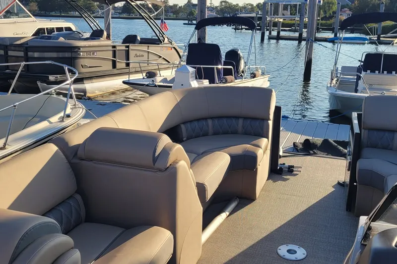 Slide: The Image of 2024 Bennington 24LXSSB pontoon boat with luxurious seating at a marina dock. - 9