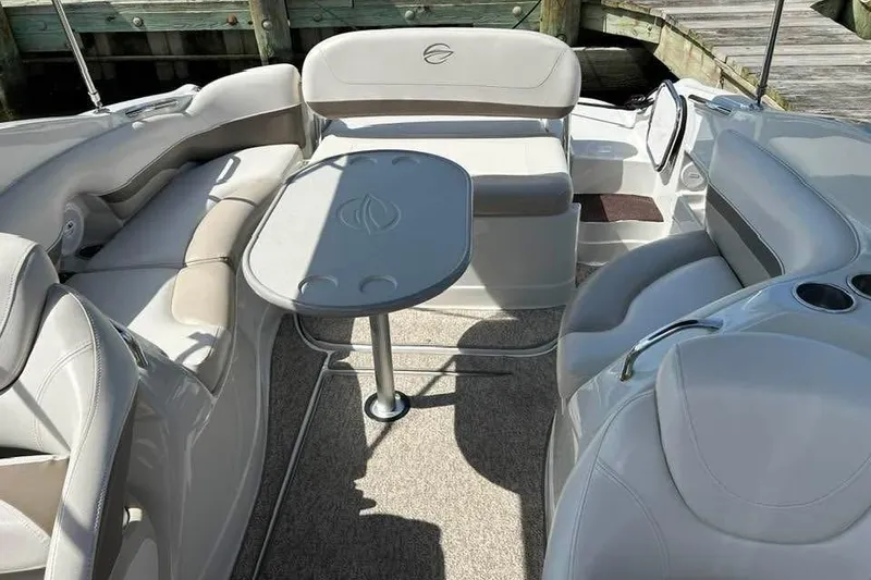 Slide: The Image of 2011 Crownline 286 SC boat interior with seating and table, docked by wooden pier. - 12