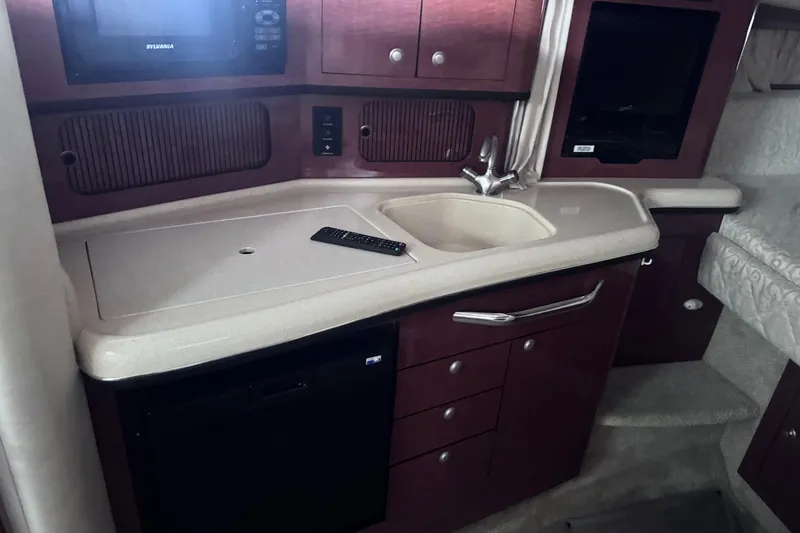 Slide: The Image of 2005 Sea Ray 300 Sundancer interior kitchen with sink, microwave, and storage cabinets. - 14