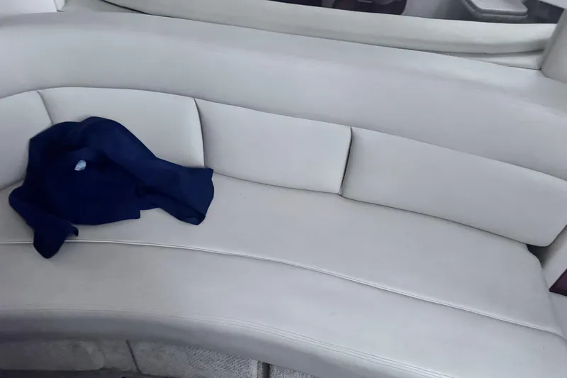 Slide: The Image of 2005 Sea Ray 300 Sundancer interior with white seating and a blue garment. - 17