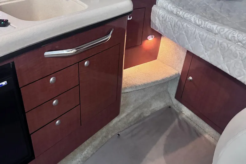 Slide: The Image of 2005 Sea Ray 300 Sundancer interior with wood cabinetry and cozy lighting. - 22
