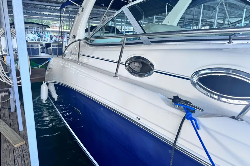 Slide: The Image of 2005 Sea Ray 300 Sundancer docked in a marina, featuring sleek design and blue hull. - 26
