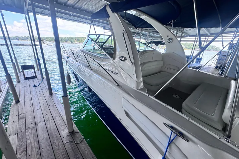 Slide: The Image of 2005 Sea Ray 300 Sundancer docked under a covered marina, showcasing sleek design and spacious seating. - 3