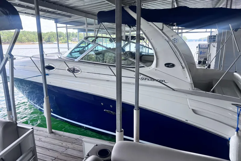 Slide: The Image of 2005 Sea Ray 300 Sundancer docked under a covered marina, featuring sleek blue and white design. - 4