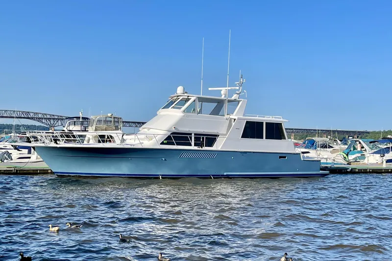 Slide: The Image of 1999 Viking Cockpit Sports Yacht cruising near palm-lined waterfront buildings. - 1